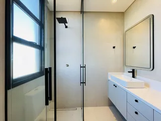 Banheiro moderno com box de vidro e bancada branca.