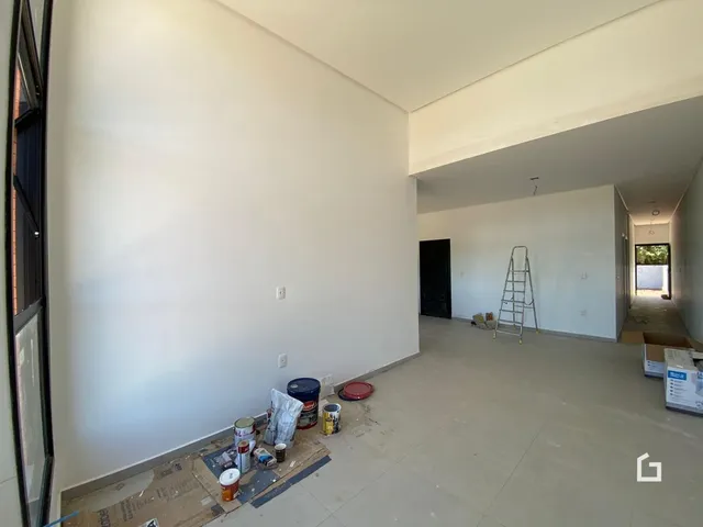 Vista interna de um espaço com paredes brancas e piso de cerâmica em uma residência.