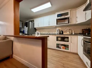 Uma cozinha com armários brancos e piso de madeira clara.