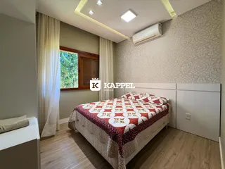 Um quarto com cama de casal e janela com cortinas brancas.