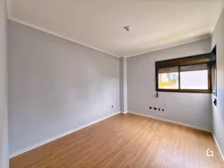 Ambiente interno de uma sala com piso de madeira clara e paredes cinzas.