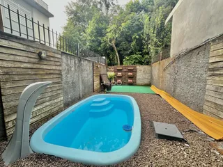 Foto de uma piscina ao ar livre cercada por muros e vegetação.