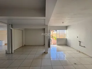 Vista interna de um corredor com piso de cerâmica e estrutura de teto exposta.