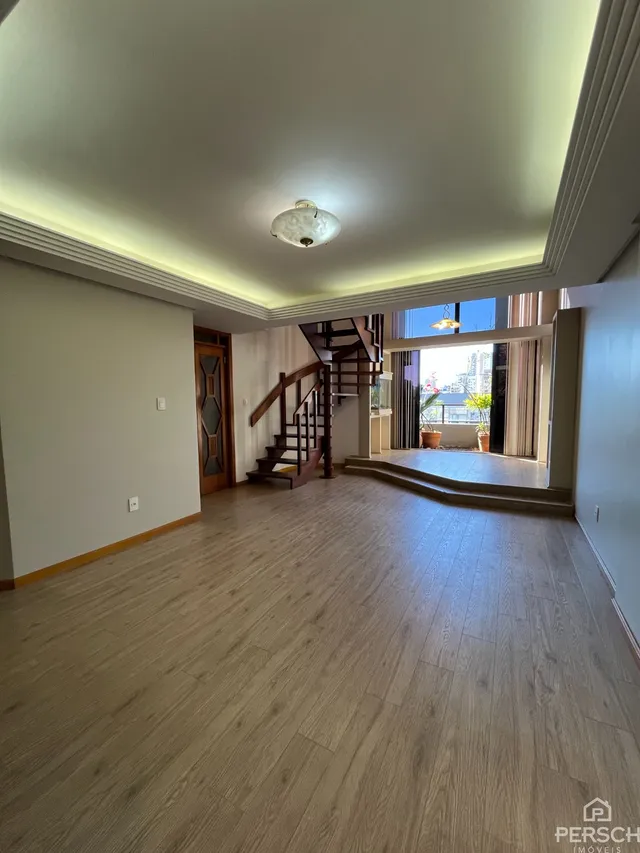Sala de estar com piso de madeira e escadaria visível.