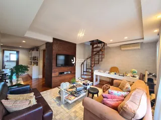 Sala de estar com sofá e escadaria de madeira em uma residência.