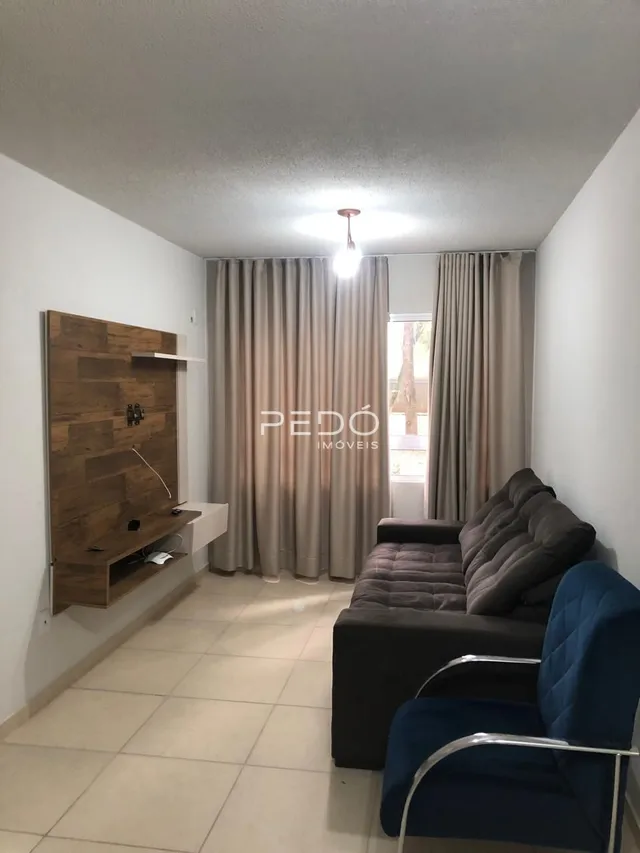 Sala de estar com cortinas e sofá em ambiente claro.