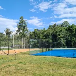 Área externa com gramado e uma quadra azul.