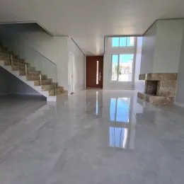 Hall de entrada com piso claro e escadaria visível.