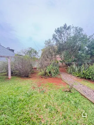 Vista externa do terreno com gramado e vegetação na propriedade.