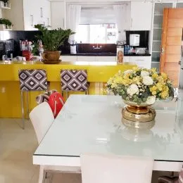 Foto de uma mesa de jantar com cadeiras brancas em um ambiente interno.