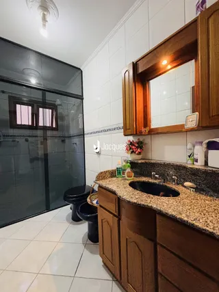Foto de um banheiro com bancada de madeira e box de vidro.