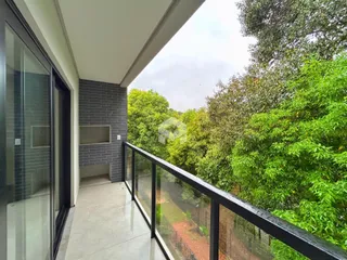 Vista de um terraço com grade de ferro e vegetação ao fundo.