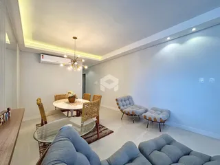 Sala de estar e jantar com móveis de vime e estofados em um apartamento.