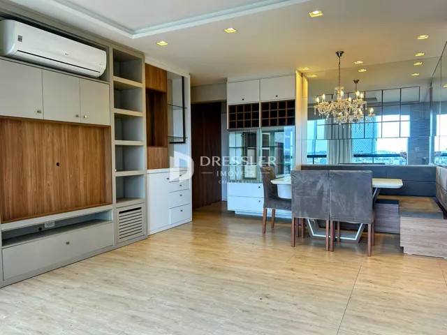 Sala de estar e jantar com piso de madeira clara e armários embutidos.