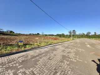 Vista da propriedade com um campo aberto e uma estrada no primeiro plano.