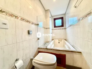 Foto interna de um banheiro com box e vaso sanitário revestido de azulejos.