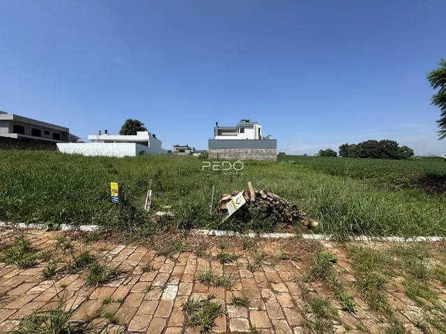 Vista de uma propriedade com campo verde e edifícios ao fundo.