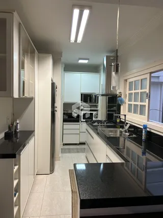 Foto de uma cozinha moderna com armários brancos e bancadas escuras.