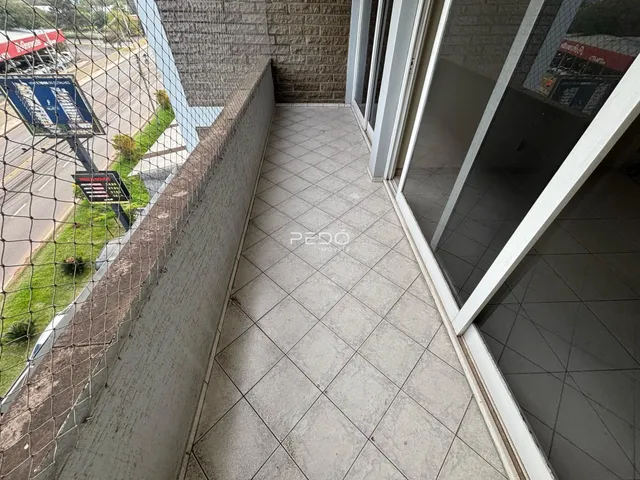 Vista externa de uma área com piso de cerâmica e cerca de tela.