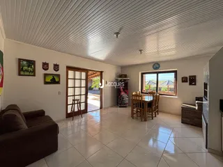 Sala de estar e jantar com piso de cerâmica clara e portas de madeira em uma residência.