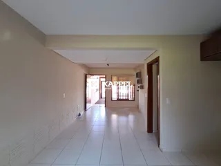 Corredor interno com piso de cerâmica claro e paredes brancas.