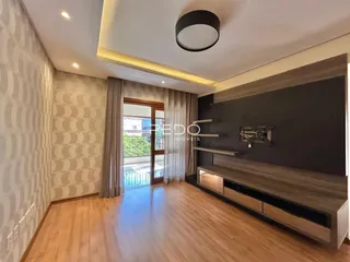 Sala de estar com piso de madeira e parede decorada em Lajeado.