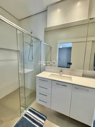 Banheiro moderno com box de vidro e bancada branca.