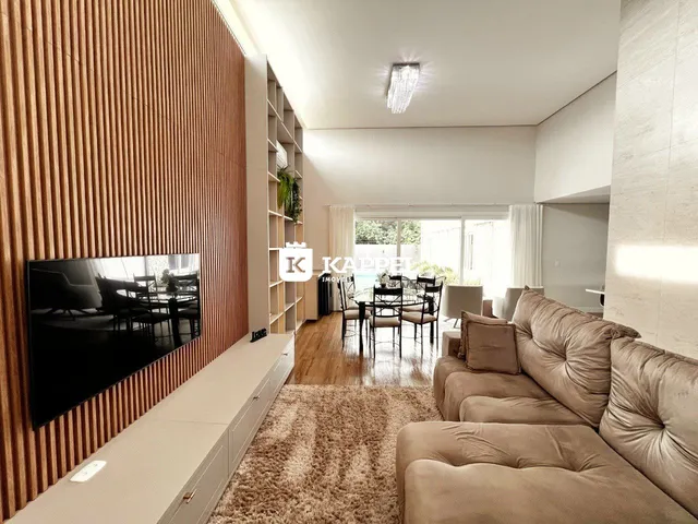 Uma sala de estar moderna com sofá grande e área de jantar ao lado.