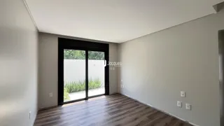 Interior com piso de madeira e porta de vidro voltada para o jardim.