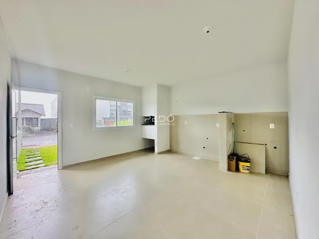 Espaço interno amplo com piso de cerâmica e porta de acesso ao exterior.