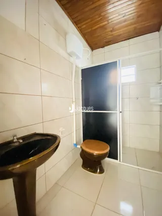 Foto de um banheiro com revestimento cerâmico branco e piso claro.