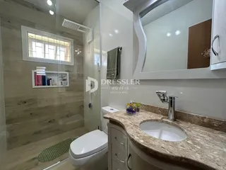 Foto de um banheiro com revestimento de cerâmica e box de vidro.