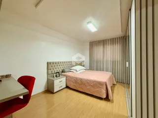 Quarto com cama e piso de madeira clara.