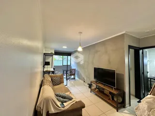 Sala de estar com sofá e televisão em um apartamento no Brasil.