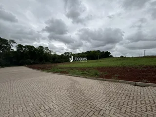 Vista externa da propriedade com área pavimentada e campo.
