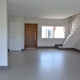 Foto de um ambiente interno com piso claro e escada visível.