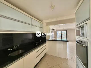 Esta é uma cozinha moderna com armários brancos e bancada preta.