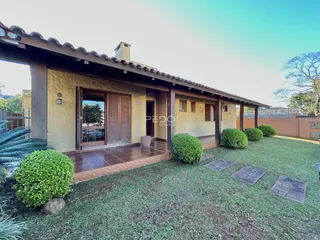 Fachada de uma casa com jardim gramado e vegetação ao ar livre.