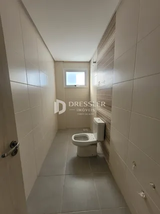 Corredor interno com revestimento de cerâmica e vaso sanitário.