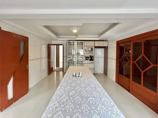 Hall de entrada de uma residência com piso claro e portas de madeira.