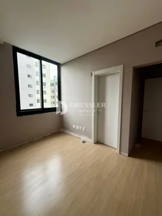 A sala apresenta um piso de madeira clara e paredes neutras.