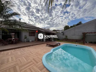 Foto externa mostrando uma piscina e um deck de madeira em uma propriedade.
