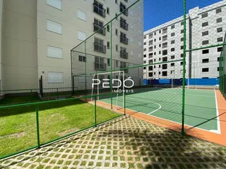 Área externa com gramado e quadra esportiva.