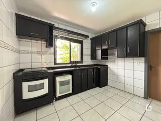 Foto da cozinha com armários pretos e revestimento branco.