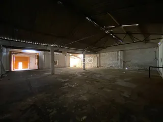 Espaço interno de um imóvel com teto alto e paredes de concreto.