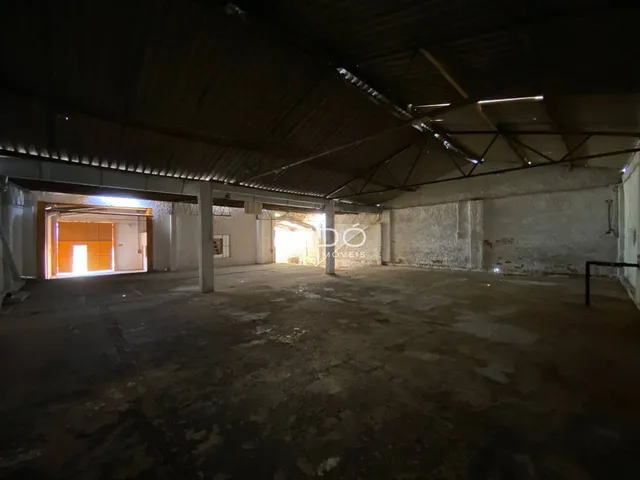 Espaço interno de um imóvel com teto alto e paredes de concreto.