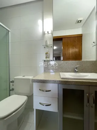 Foto do interior de um banheiro com revestimento cerâmico branco.