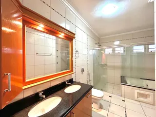 Banheiro com bancada dupla e box de vidro.