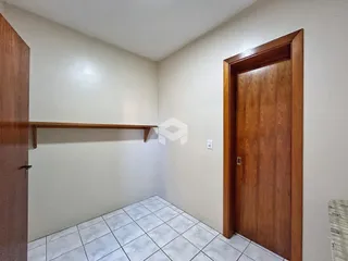 Vista interna de um corredor com piso de cerâmica e porta de madeira.