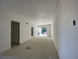 Corredor interno com paredes brancas e piso de concreto aparente.